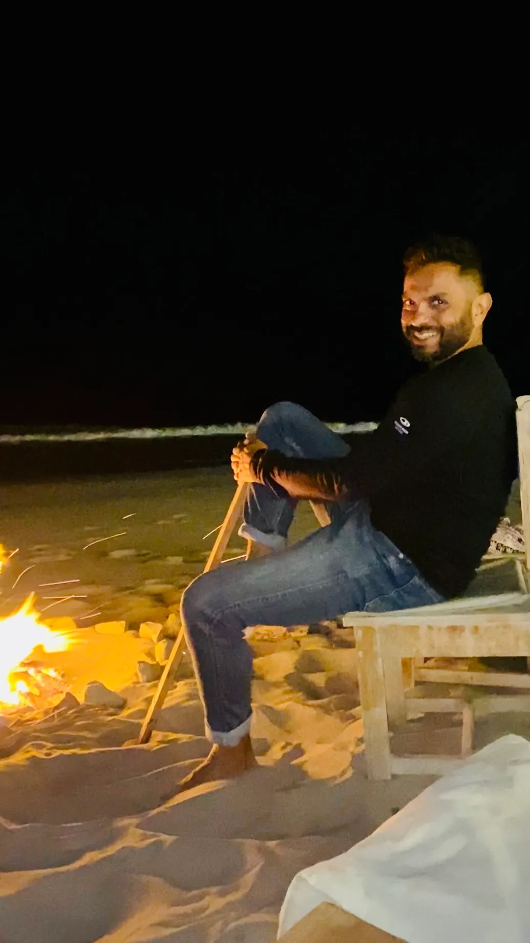 Zaheer by a fire on the beach at night